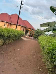 a house with a red roof on a dirt road at Binga villa in Kisoro