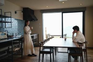 a man and a woman sitting at a table in a kitchen at THE SHIKAKA Hotel&Resort BUDOUNOKI in Itoshima