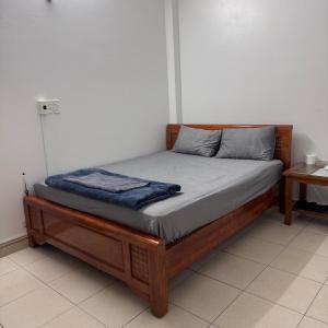 a bed with a wooden frame in a room at Nhà Nghỉ Bình An in Kỳ Lừa