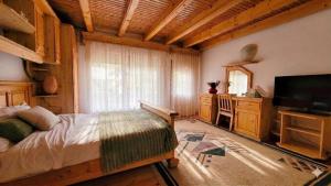 a bedroom with a bed and a flat screen tv at Cabana de la rau Satic in Sătic