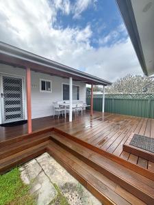 a wooden deck with a table and chairs on it at Wenlaw Cottage Rear Hat Head - Bring your own linen. in Hat Head