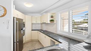 a kitchen with white cabinets and a large window at The Entrance Unit 5 in Kawana Waters +6 photos