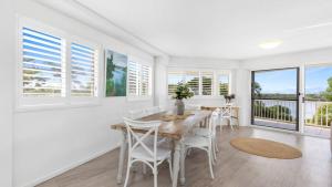 a dining room with a table and chairs and windows at The Entrance Unit 5 in Kawana Waters