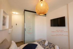 a bedroom with a bed and a television and a chandelier at Sea & Desert Retreat in Arad