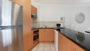 a kitchen with wooden cabinets and a stainless steel refrigerator at Grand Pacific Unit 19 in Caloundra