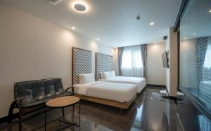 a bedroom with a white bed and a couch and a chair at 부산 연산동 MU Plus 호텔 in Kŏje