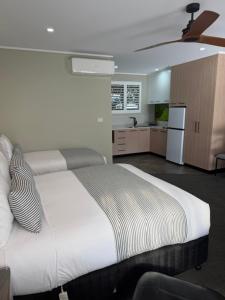 a bedroom with a large white bed and a kitchen at Barooga River Gums Motor Inn in Barooga
