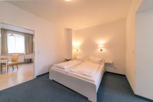 a bedroom with a white bed and a table at Gästehaus Am Hothertor in Görlitz