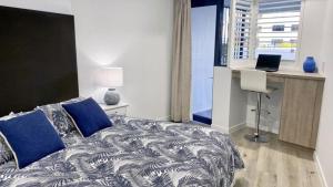 a bedroom with a bed and a desk with a laptop at Grand Pacific Unit 10 in Caloundra