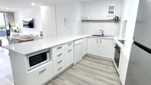 a white kitchen with white cabinets and a sink at Grand Pacific Unit 10 in Caloundra