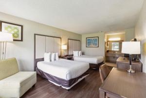 a hotel room with two beds and a couch at Ramada by Wyndham Houma in Houma +11 photos