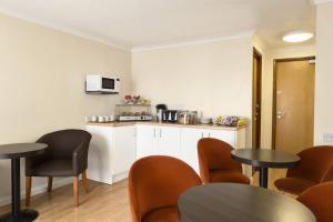 a room with two tables and chairs and a kitchen at Days Inn Hotel Leicester in Leicester
