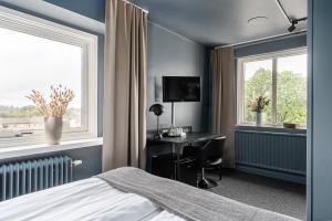 a bedroom with a bed and a desk and two windows at Stora Hotellet Markaryd in Markaryd
