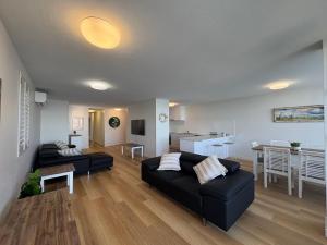 a living room with a black couch and a kitchen at Pumicestone Chase Unit 8 in Caloundra