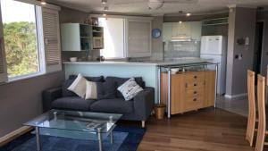 a living room with a couch and a kitchen at Outlook Unit 7 in Kawana Waters