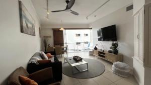 a living room with a couch and a flat screen tv at Rolling Surf Resort Unit 48 in Caloundra