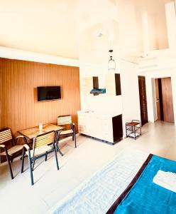 a living room with a table and chairs and a television at Dostar Beach Hotel - Достар Жағажай Қонақүйі in Aktau