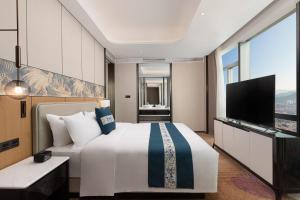 a hotel room with a bed and a flat screen tv at Wyndham Shanwei Haifeng in Shanwei