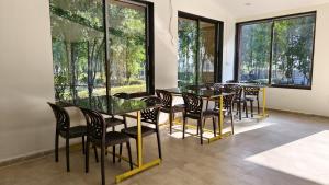 a dining room with tables and chairs and windows at Nal Village Resort By Explore With Nirav in Rupāwati