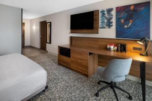 a hotel room with a bed and a desk with a television at Wingate by Wyndham Geneva at SPIRE Academy in Geneva +27 photos