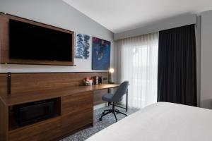 a hotel room with a bed and a desk with a television at Wingate by Wyndham Geneva at SPIRE Academy in Geneva