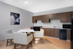 a kitchen with white chairs and a table and a counter at Wingate by Wyndham Geneva at SPIRE Academy in Geneva