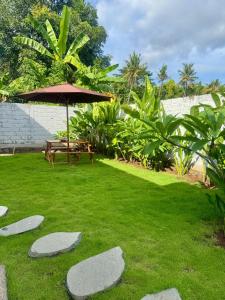 a garden with a picnic table and an umbrella at Griya Becik Lovina - Private Pool Villa near Lovina Dolphin Spot in Lovina