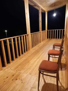two chairs sitting on a wooden balcony at night at Ani Center Hotel in Dovekh +3 photos