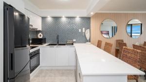 a kitchen with white cabinets and a black refrigerator at Grand Pacific Unit 104 in Caloundra +6 photos