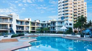 a swimming pool in front of some apartment buildings at Grand Pacific Unit 104 in Caloundra