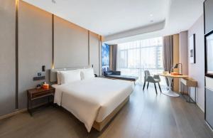 a bedroom with a large white bed and a desk at Atour Hotel Altay in Altay