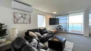 a living room with a leather couch and a television at Pumicestone Chase Unit 5 in Caloundra