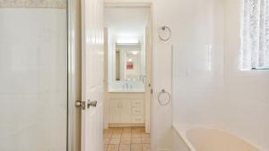 a white bathroom with a tub and a sink at Unit 2 'fair Haven' Kings Beach in Caloundra +6 photos