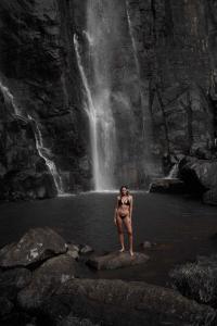 a woman standing on a rock in front of a waterfall at Kaya Retreat in Diyatalawa