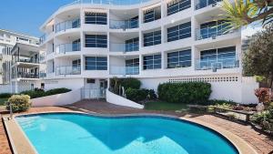 an apartment building with a swimming pool in front of it at Absolute Waterfront With Rooftop! in Caloundra