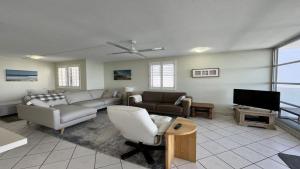 a living room with couches and a flat screen tv at Absolute Waterfront With Rooftop! in Caloundra