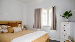 a bedroom with a bed with a white dresser and a window at Blue Beach House in Caloundra