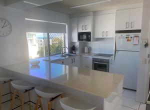 a kitchen with white cabinets and a counter with stools at Spinnaker Seas Unit 8 in Caloundra