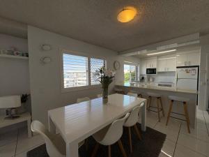 a white kitchen with a white table and chairs at Spinnaker Seas Unit 8 in Caloundra