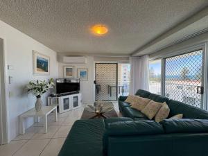 a living room with a green couch and a tv at Spinnaker Seas Unit 8 in Caloundra