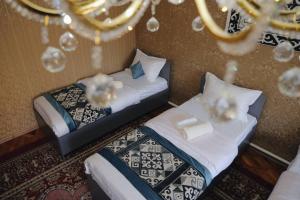 two twin beds in a room with a chandelier at Nomad Guest House Osh in Osh