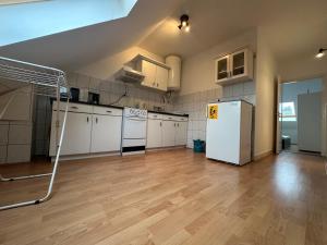 a large kitchen with white appliances and wooden floors at Arnold Apartmanház in Bük