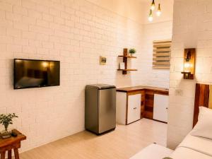 a kitchen with a refrigerator and a tv on a wall at Alona Marga in Panglao Island