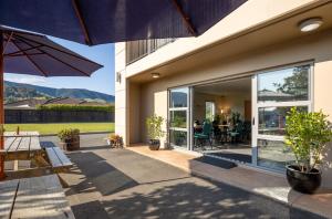 a patio with a table and an umbrella at Saxton Lodge in Nelson