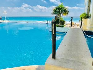 a swimming pool with the ocean in the background at Ventanas al Paraiso Apartment Cancun in Cancún
