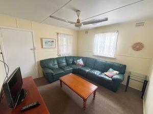a living room with a green couch and a table at Bundi Hat Head - Bring your own linen in Hat Head