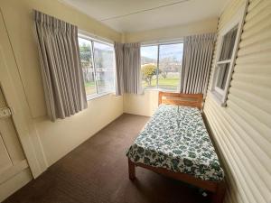 a bedroom with a bed and two windows at Bundi Hat Head - Bring your own linen in Hat Head