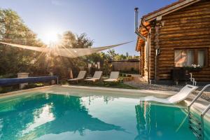 a swimming pool with chairs and a house at Holzhaus in Sadu