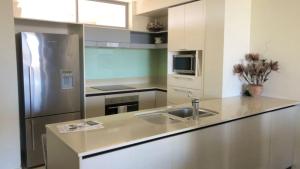 a kitchen with a stainless steel refrigerator and a sink at Amazing Views, Walk Everywhere! in Caloundra