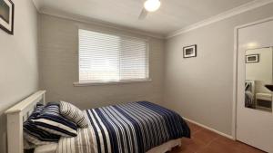 a small bedroom with a bed and a window at Drakes Hideaway in Golden Beach